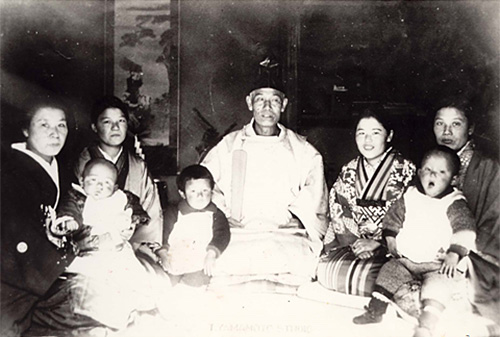 A family photo with the father at the center. Yawning little Satoshi sits on his mother’s lap (far right)